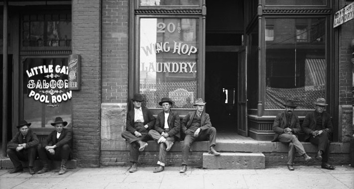 Men sitting outside a laundry shop on Plum Alley in 1910.