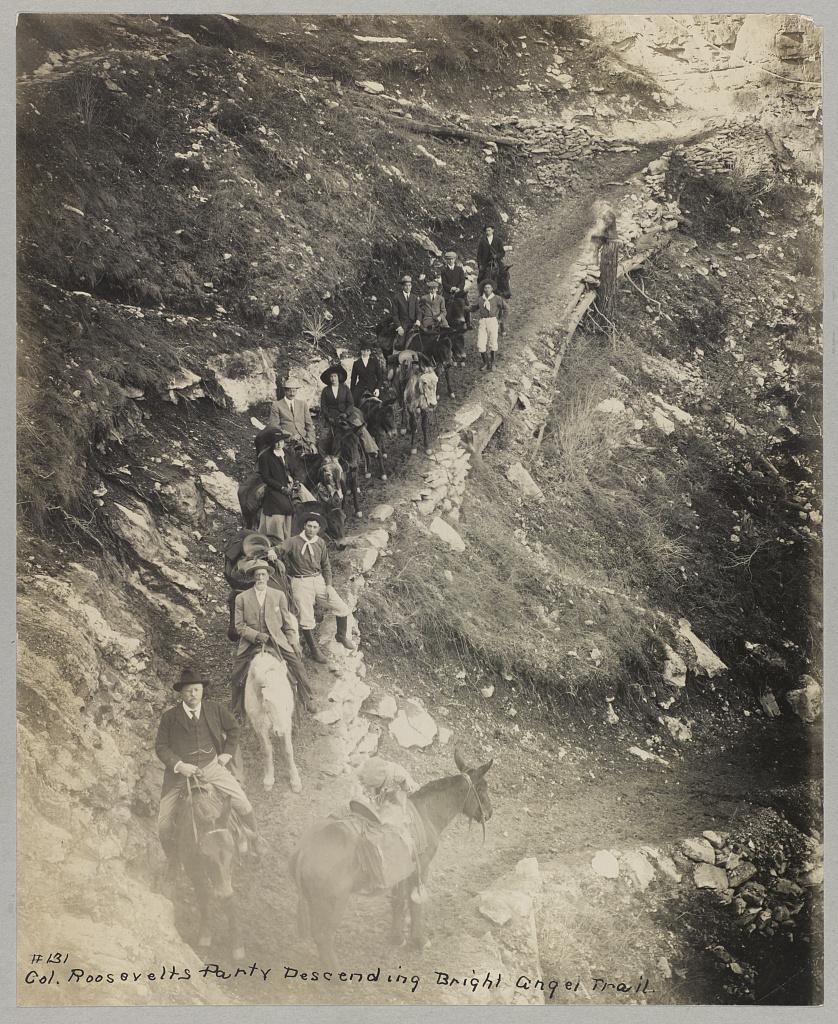 Down a winding pathway, Theodore Roosevelt and others ride mules down Bright Angel Trail in the Grand Canyon